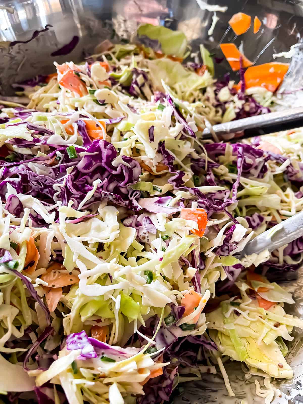 large aluminum mixing bowl with freshly tossed creamy coleslaw