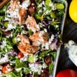 Vibrant mixed vegetable and Greek salmon salad featuring cherry tomatoes, fresh herbs, and creamy dressing, perfect for healthy eating.