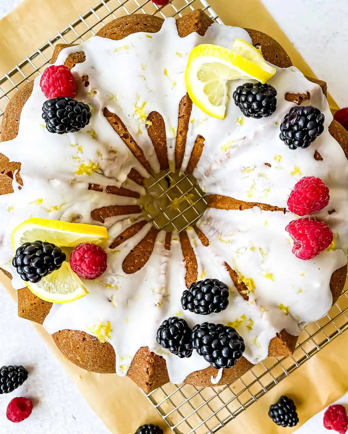 Lemon bundt cake with a lemon glaze, garnished with raspberries, black berries, and lemon slices and zest