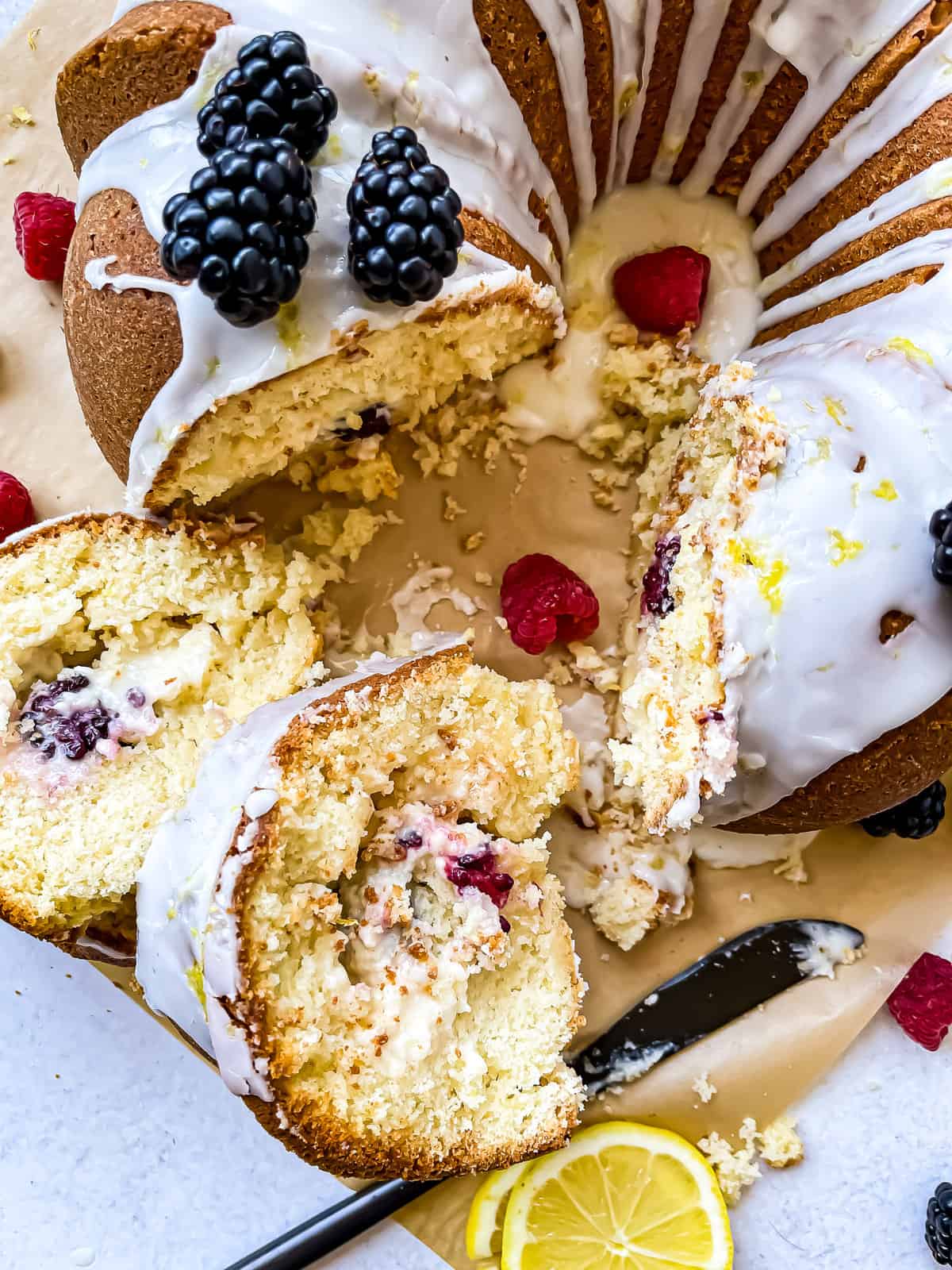 Lemon bundt cake with a lemon glaze, garnished with raspberries, black berries, and lemon slices and zest