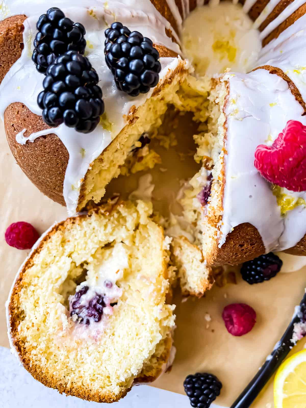 Lemon bundt cake with a lemon glaze, garnished with raspberries, black berries, and lemon slices and zest