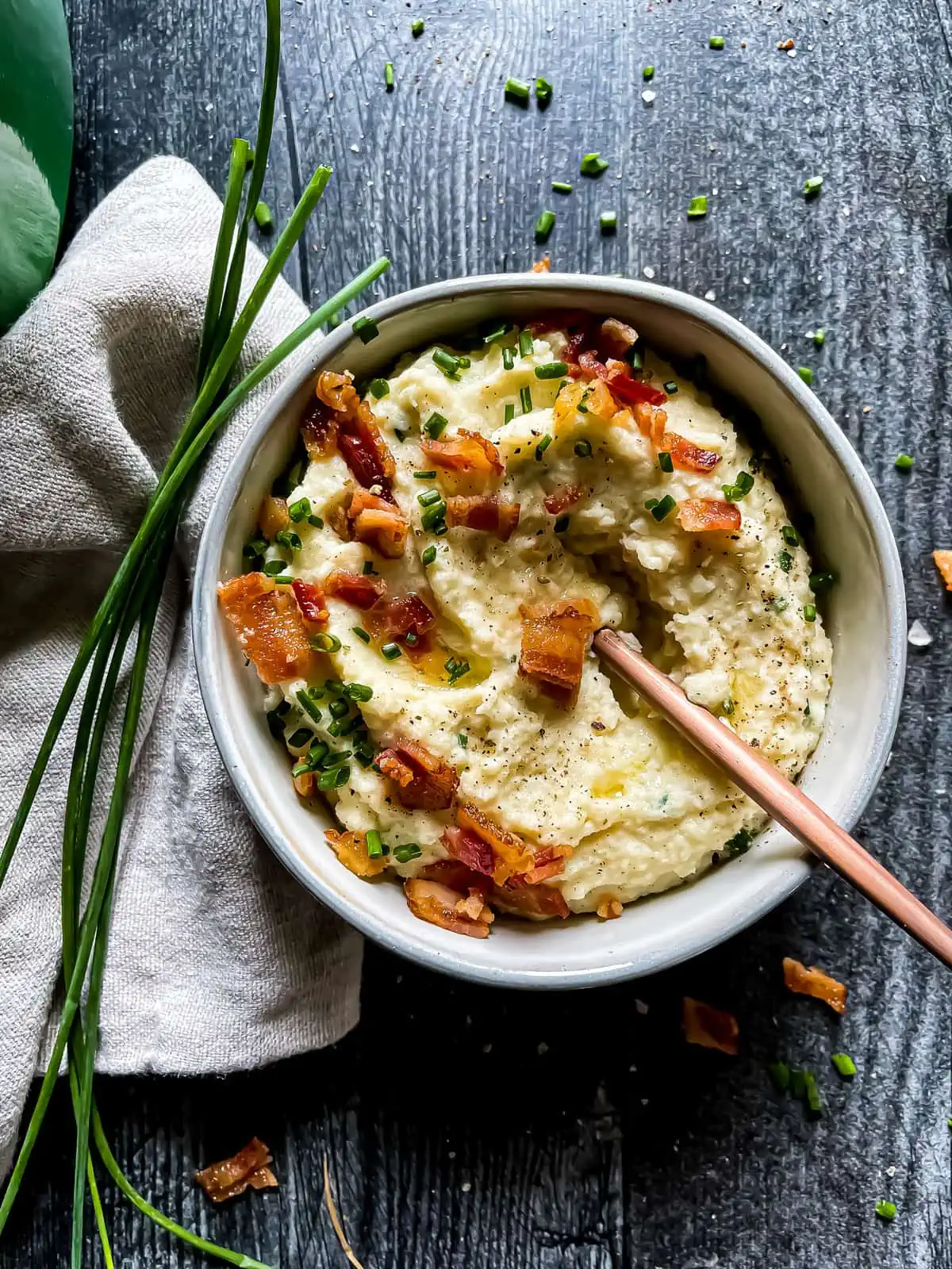 mashed cauliflower garnished with chives, bacon