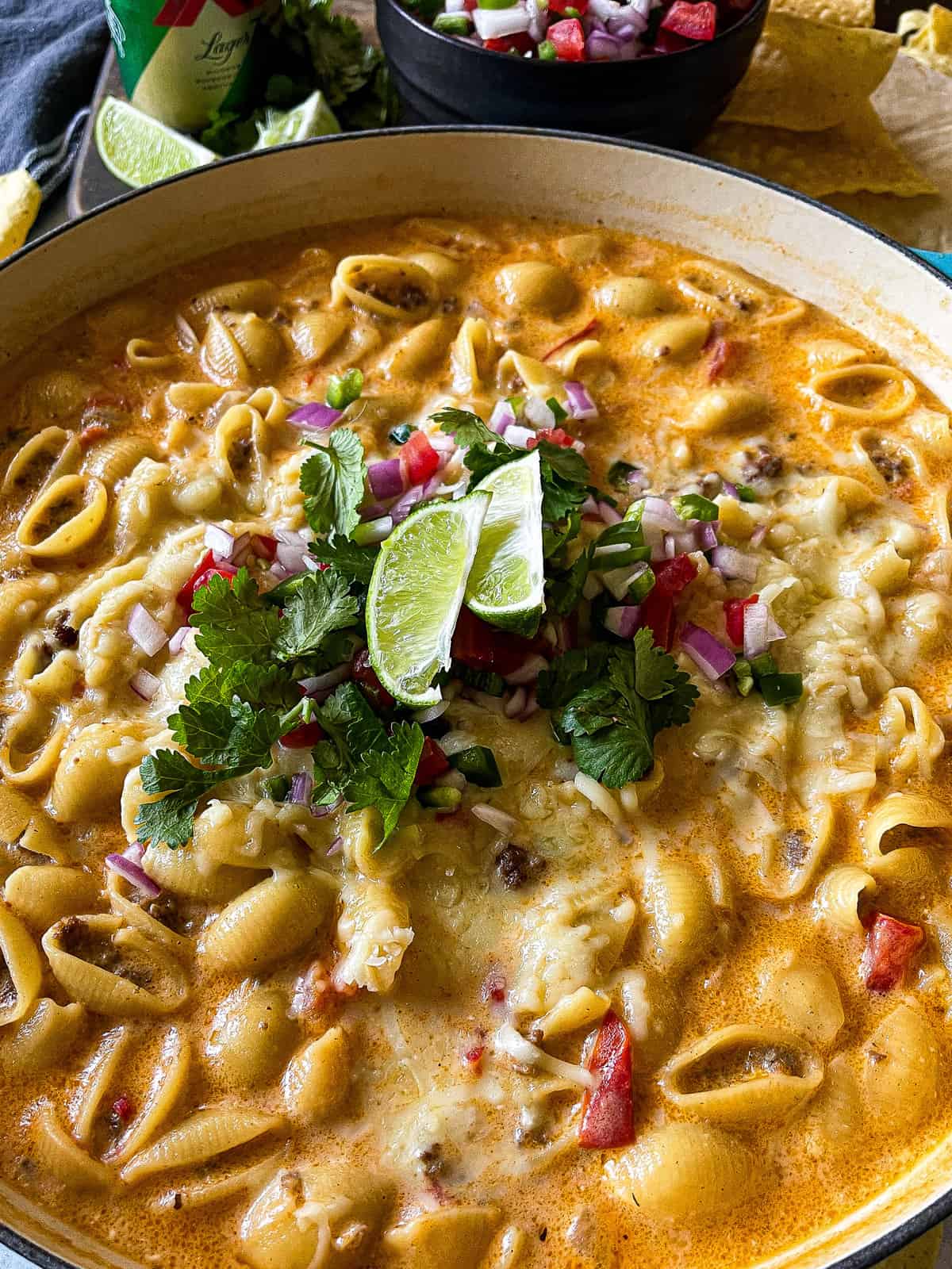taco pasta recipe served in a large braising pan, garnished with pico de gallo and lime slices