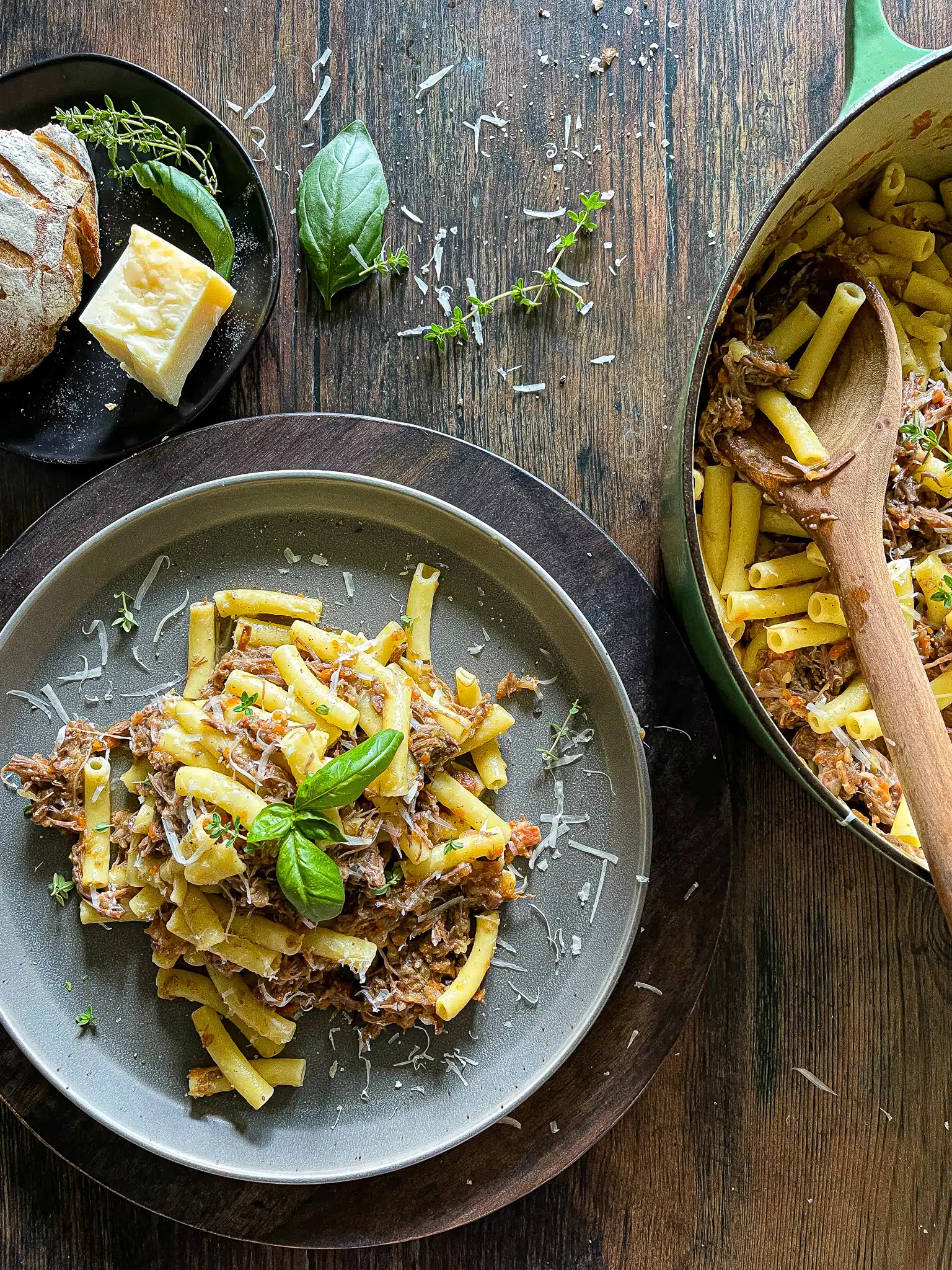 pasta alla genovese - an onion and beef ragù served on a plate from a dutch oven, garnished with parmesan cheese and fresh herbs