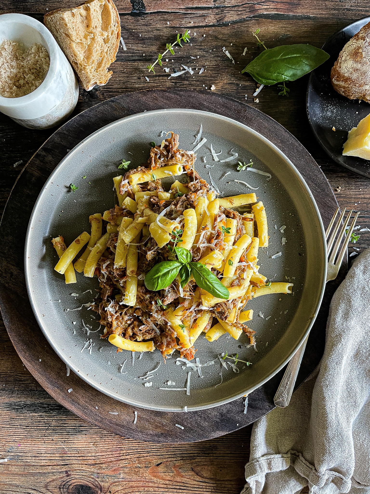 pasta alla genovese - an onion and beef ragù served on a plate from a dutch oven, garnished with parmesan cheese and fresh herbs