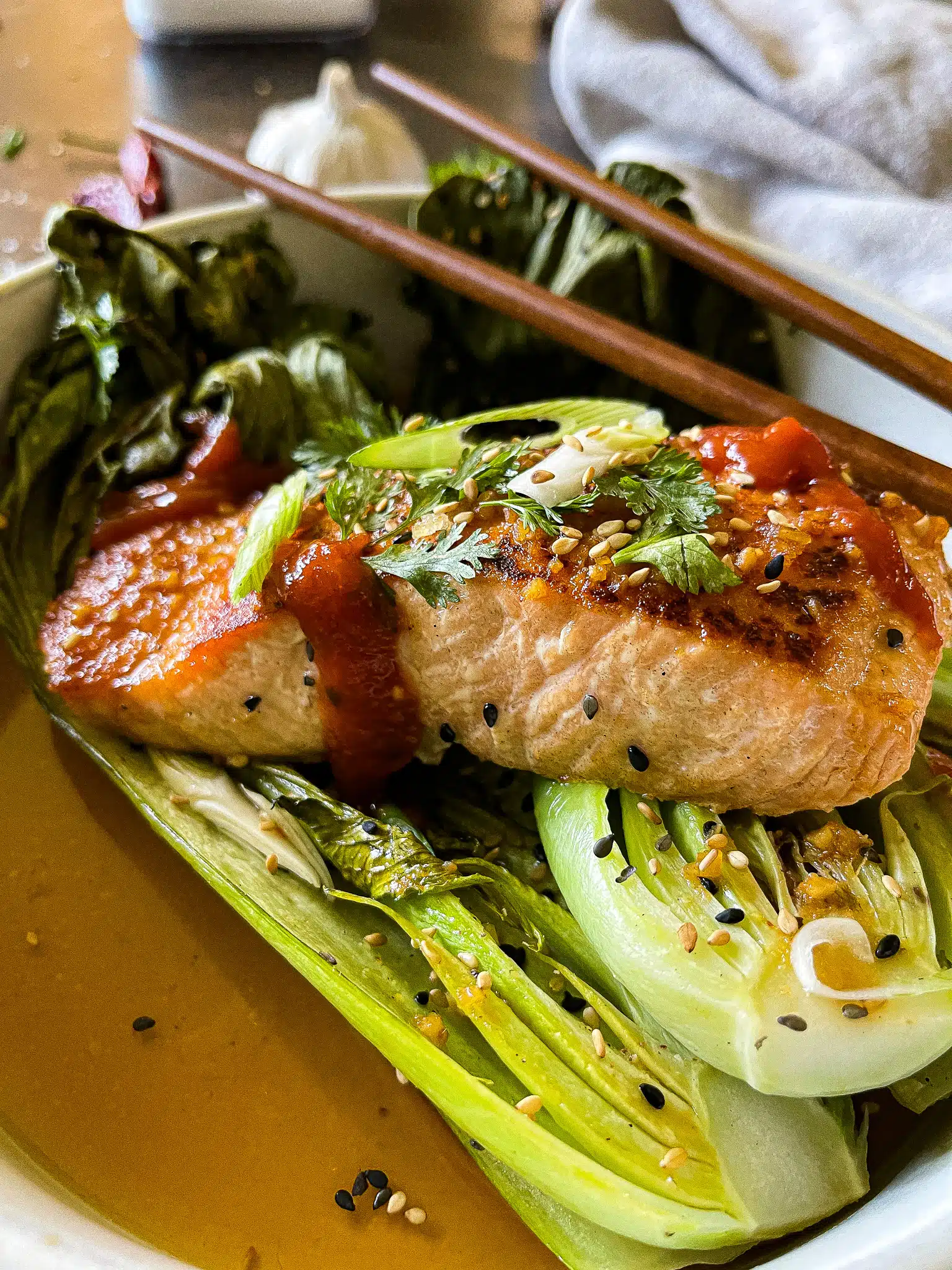 soy ginger salmon served with roasted bok choy, garnished with cilantro, green onion, and sesame seeds