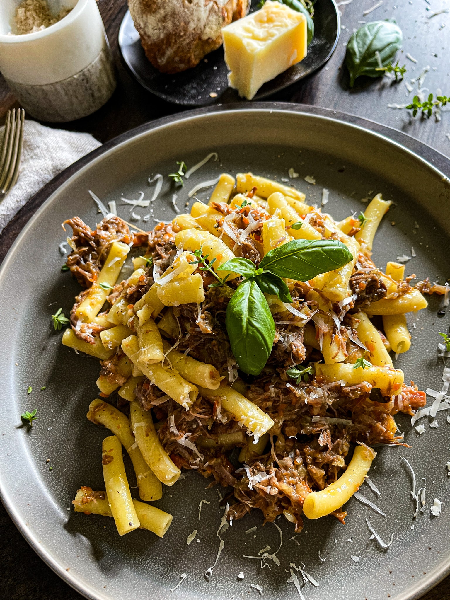 pasta alla genovese - an onion and beef ragù served on a plate from a dutch oven, garnished with parmesan cheese and fresh herbs