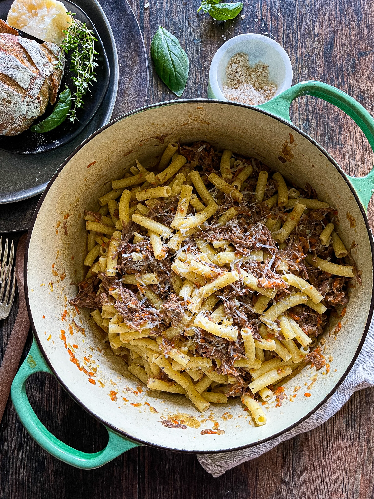 pasta alla genovese - an onion and beef ragù in a dutch oven, garnished with parmesan cheese and fresh herbs