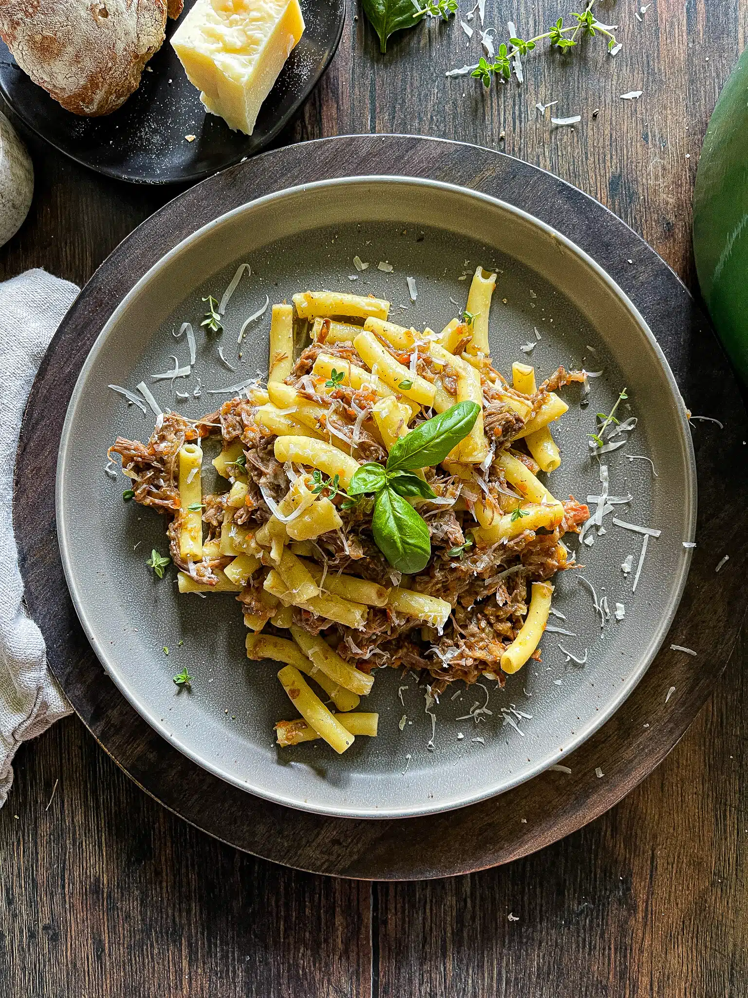 onion and beef ragù served on a plate from a dutch oven, garnished with parmesan cheese and fresh herbs