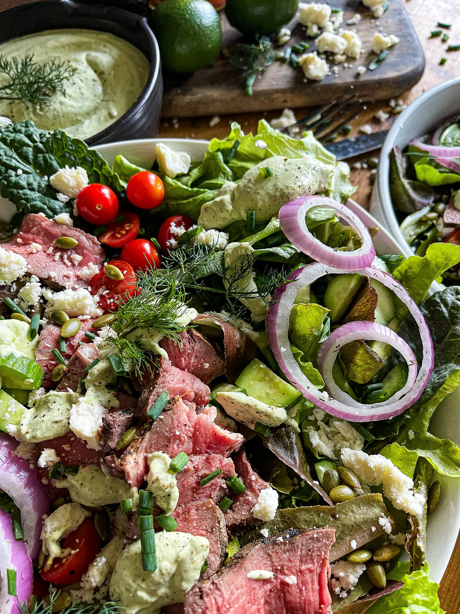 bowl of mixed greens, steak, tomatoes, pickled onions, cucumbe, pepitas, queso fresco and avocado ranch dressing