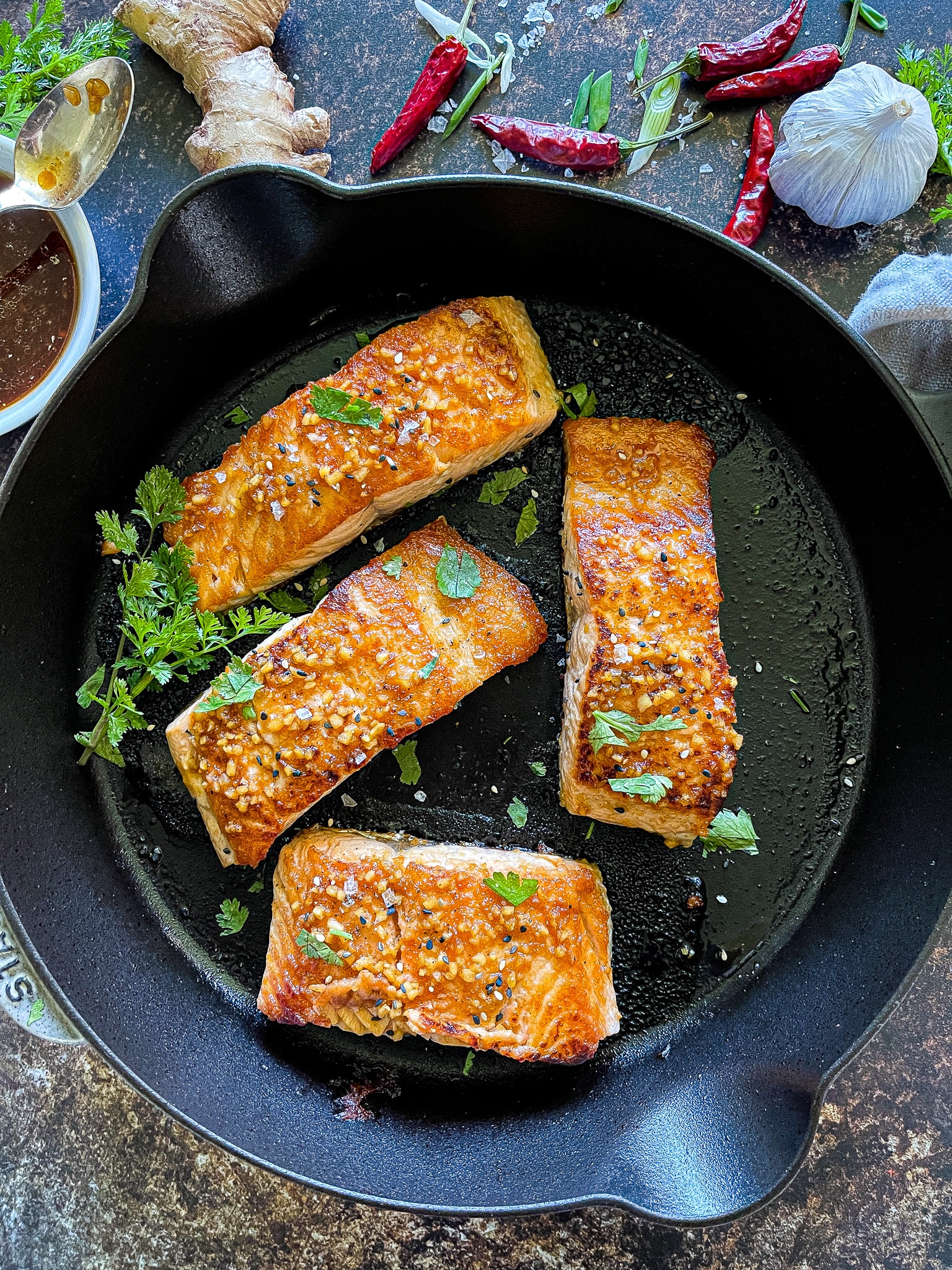 salmon in a cast iron skillet garnished with cilantro leaves