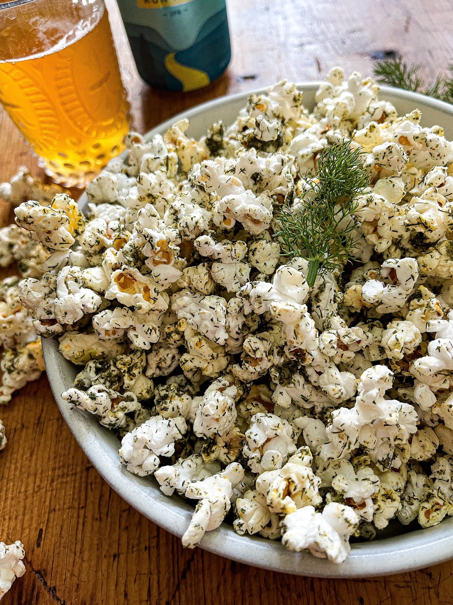 a large bowl of dill pickle popcorn, garnished with fresh dill