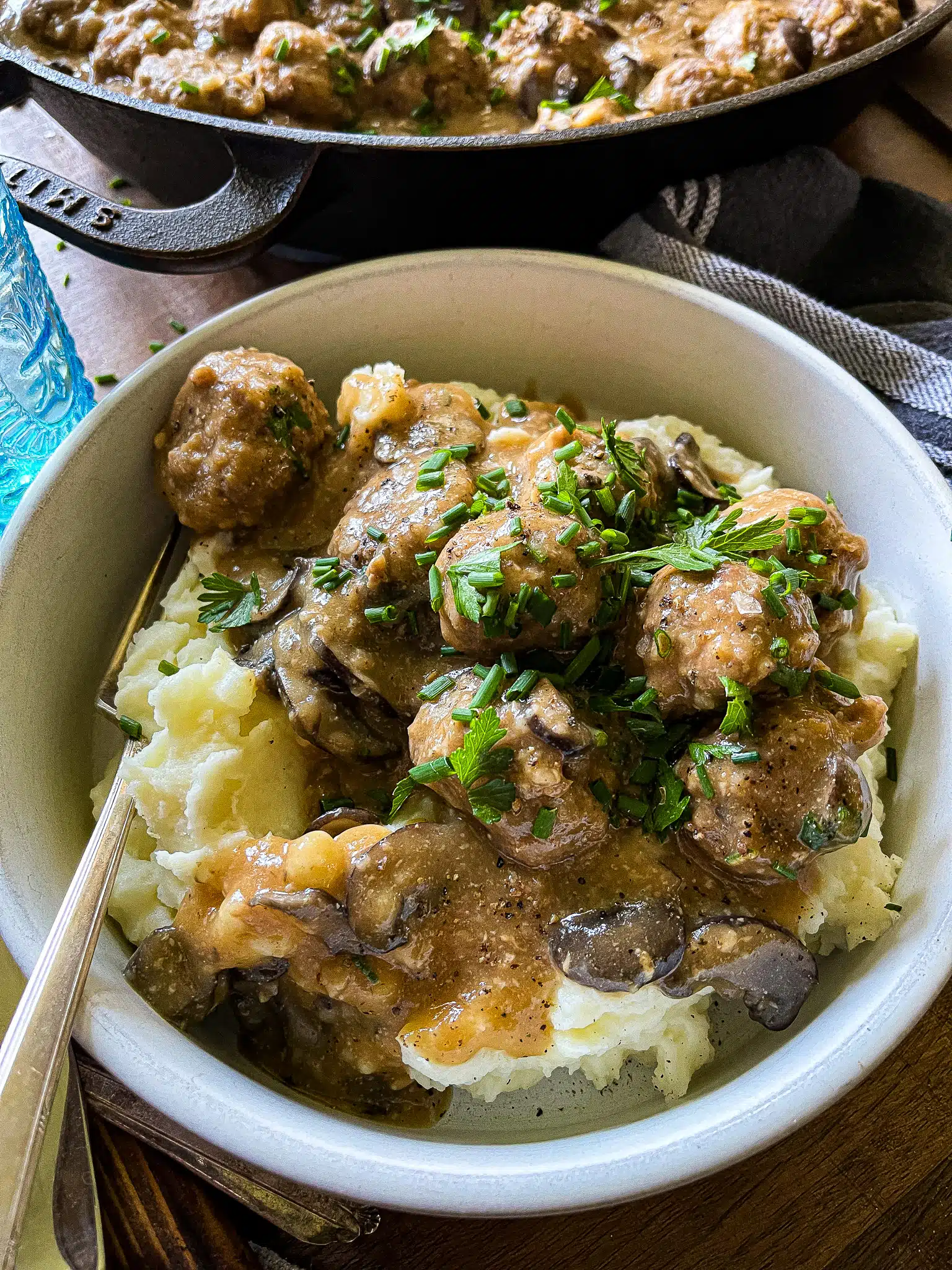 meatballs in a bowl with chives and parsley garnish