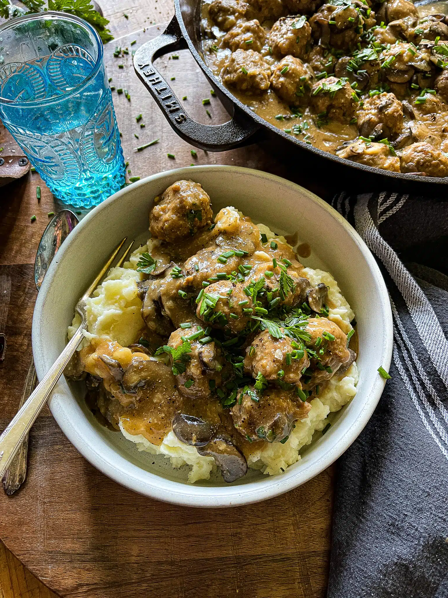 salisbury steak meatballs served in a white bowl, garnished with parsley and chives