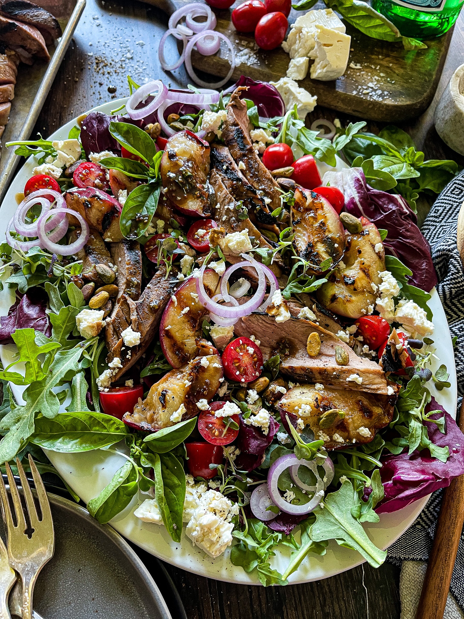 grilled peach salad with pork tenderloin on a platter