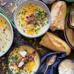 bowls of baked potato soup with crusty bread on the side