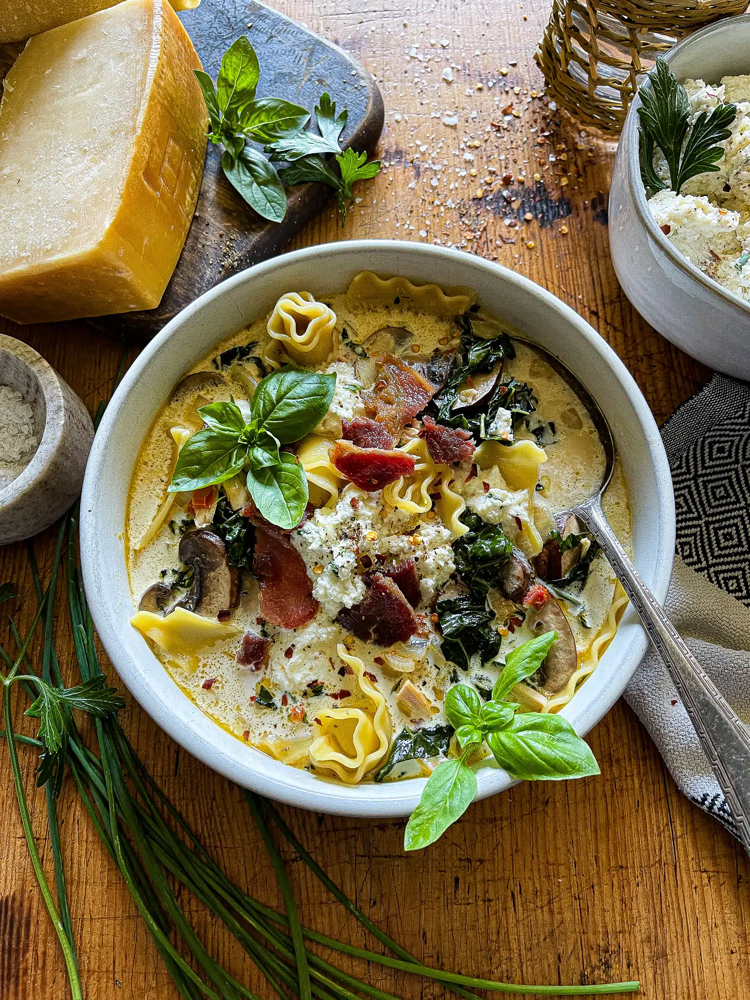 A bowl of white lasagna soup with basil garnishes.