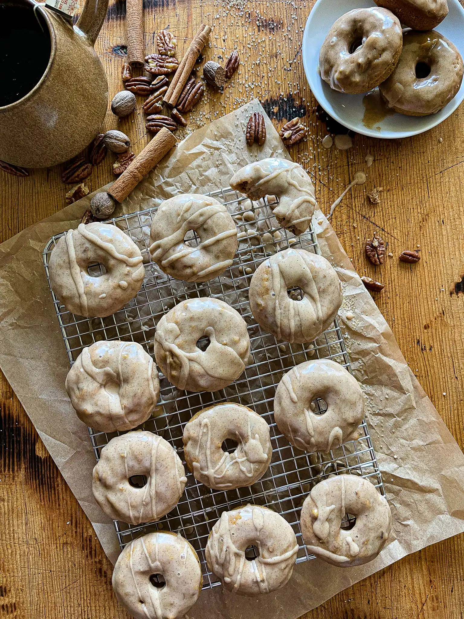 This is a picture of a baking rack covered with apple cider donuts and a maple cinnamon glaze.