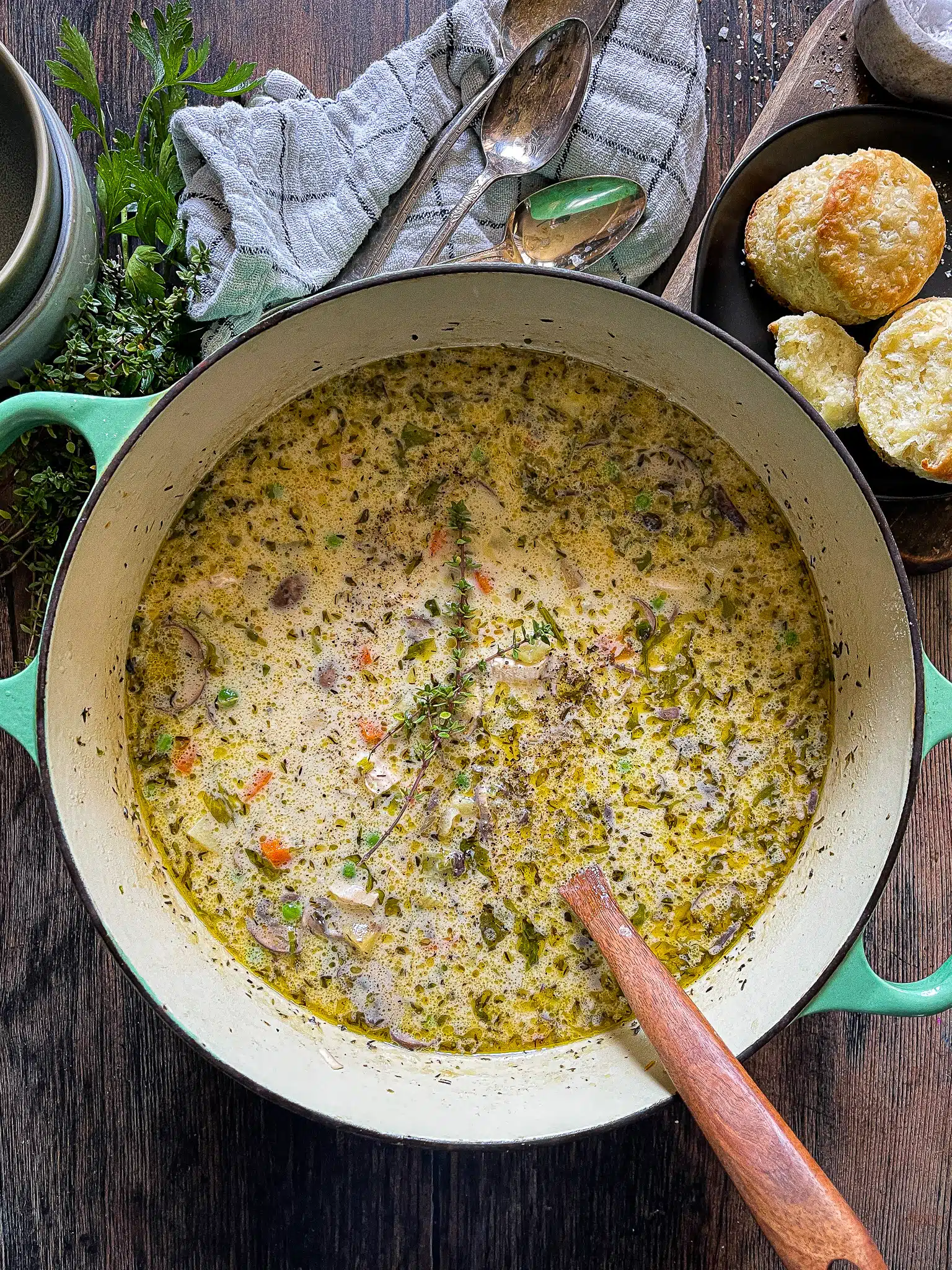 This is a dutch oven full of chicken pot pie soup with a fresh thyme sprig for garnish.