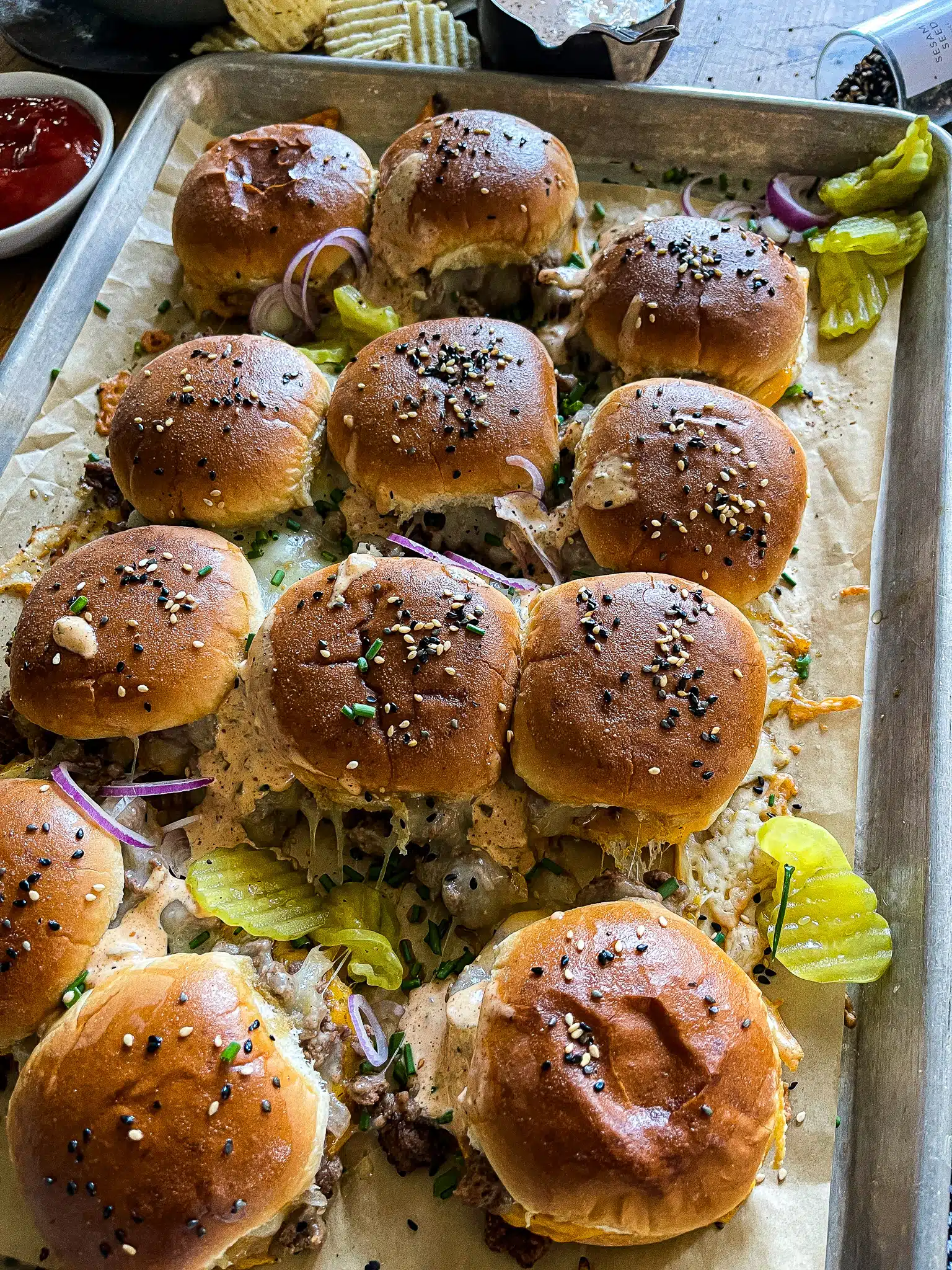 This is a picture of a sheet pan of cheeseburger sliders with gooey cheese and burger sauce.