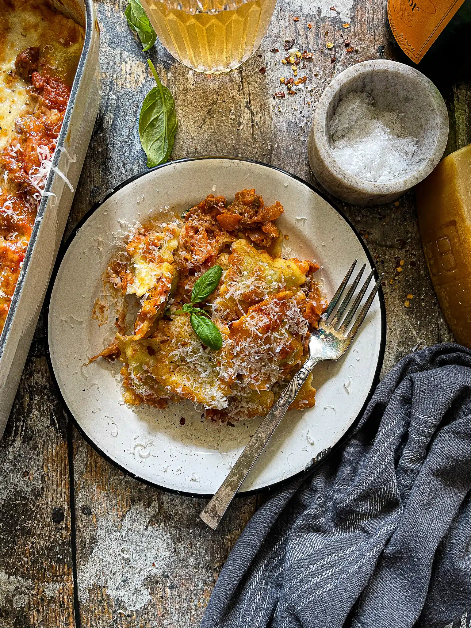 This is a picture of a plate of Ravioli Lasagna, garnished with fresh basil and grated parmesan cheese.