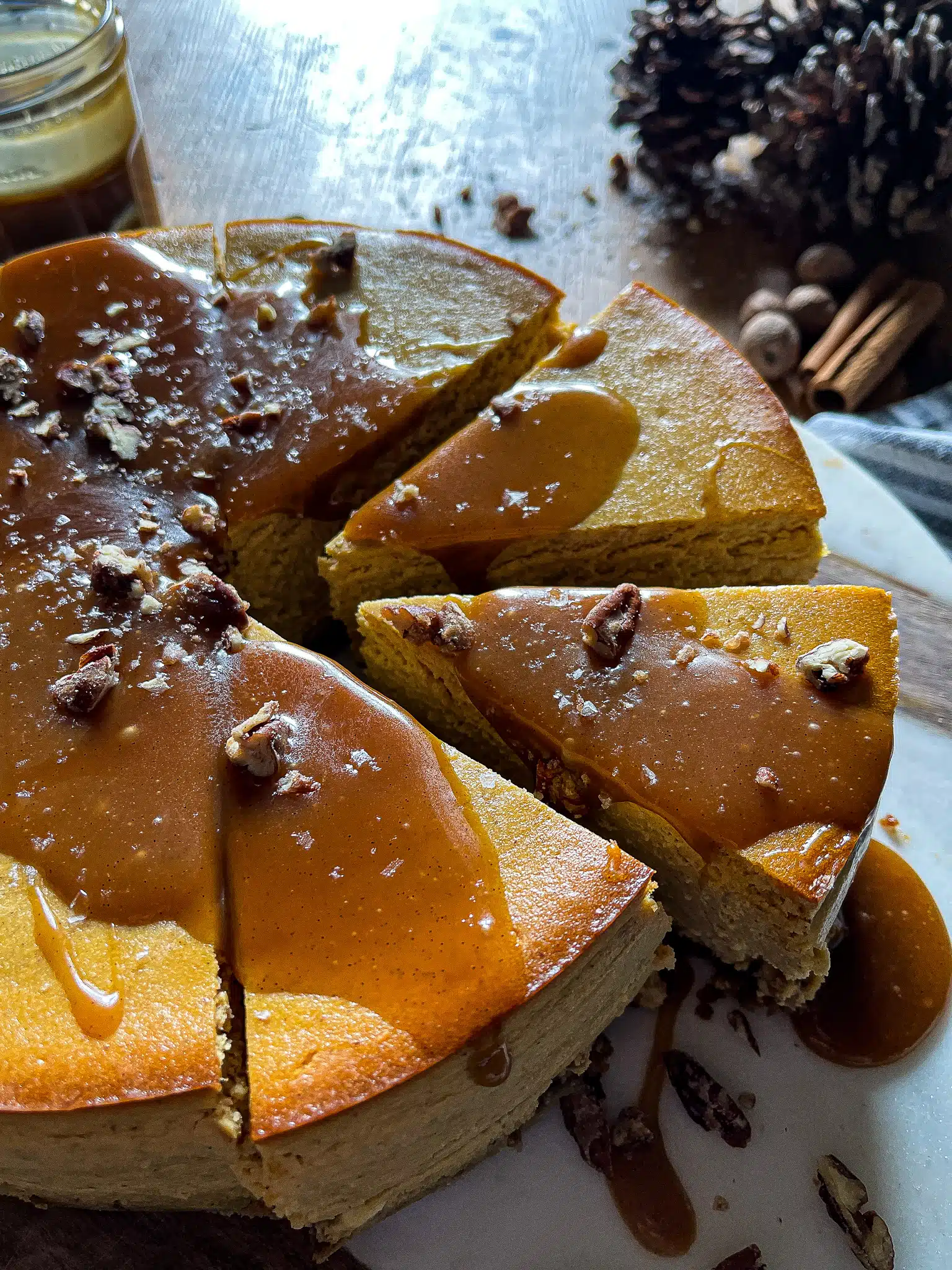 This is a picture of the slice of pumpkin cheesecake with a salted caramel drizzle. the cheesecake is also garnished with flaky sea salt, candied pecans.