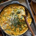 This is a picture of creamy broccoli rice casserole baked in a cast iron skillet garnished with fresh chives