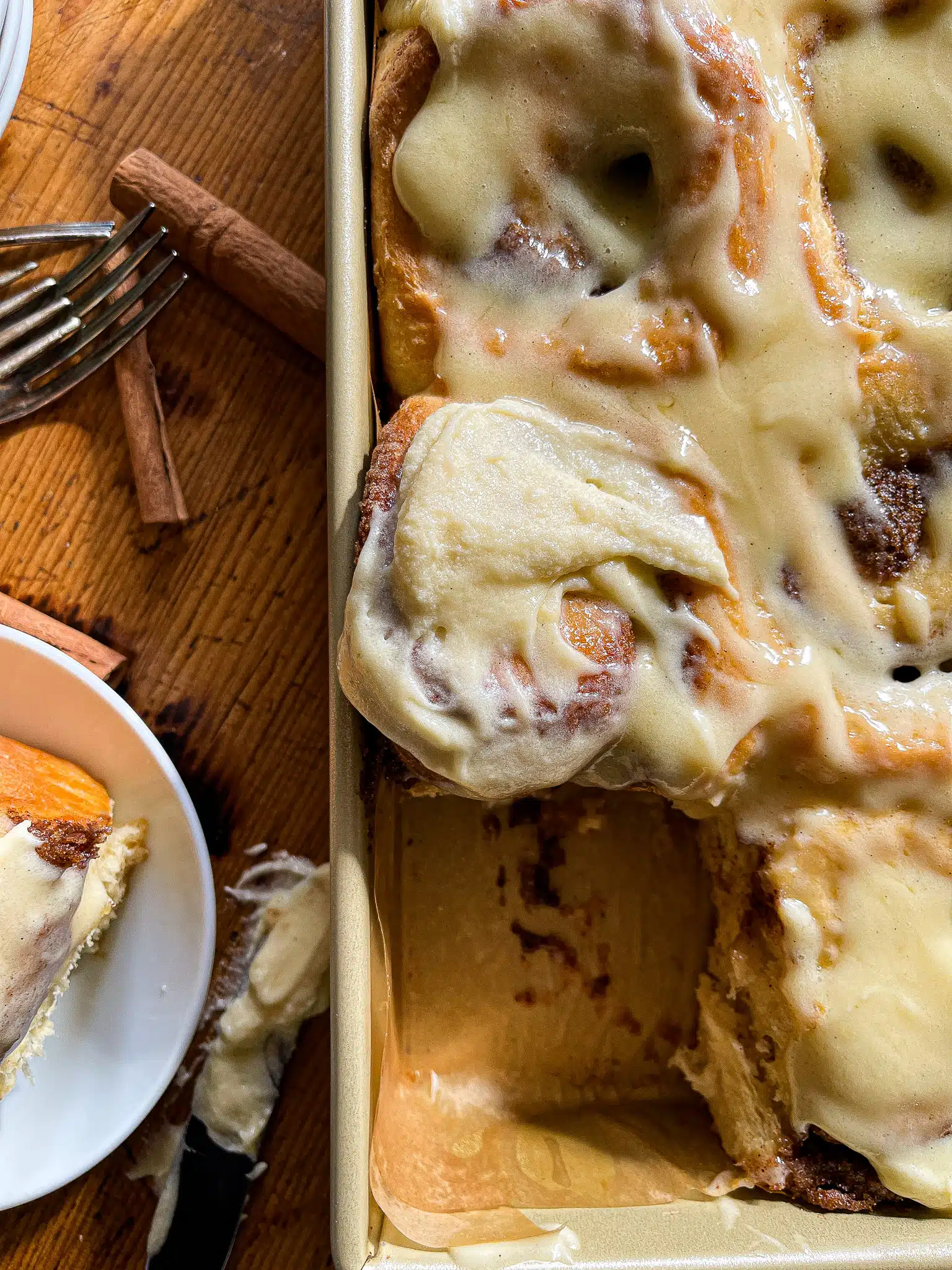 This is a picture of a baking dish of cinnamon rolls with one roll removed and sitting on a small white plate