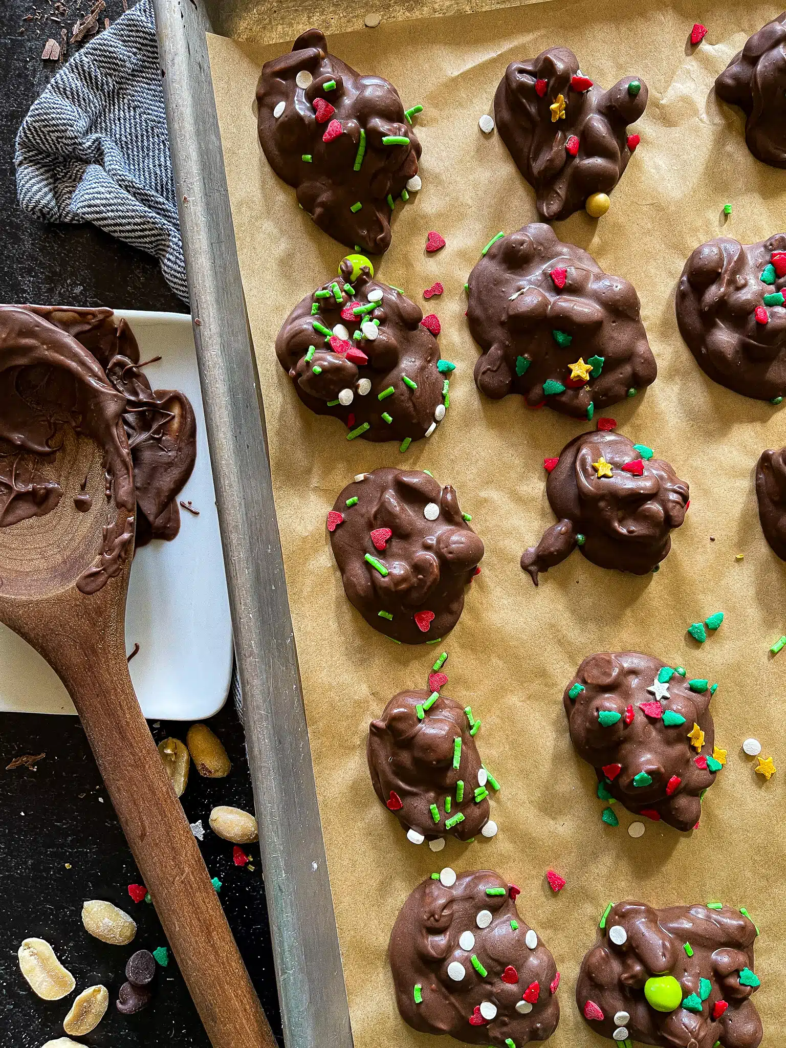 this is a picture of peanut clusters topped with red and green Christmas spinkles on a parchment paper background