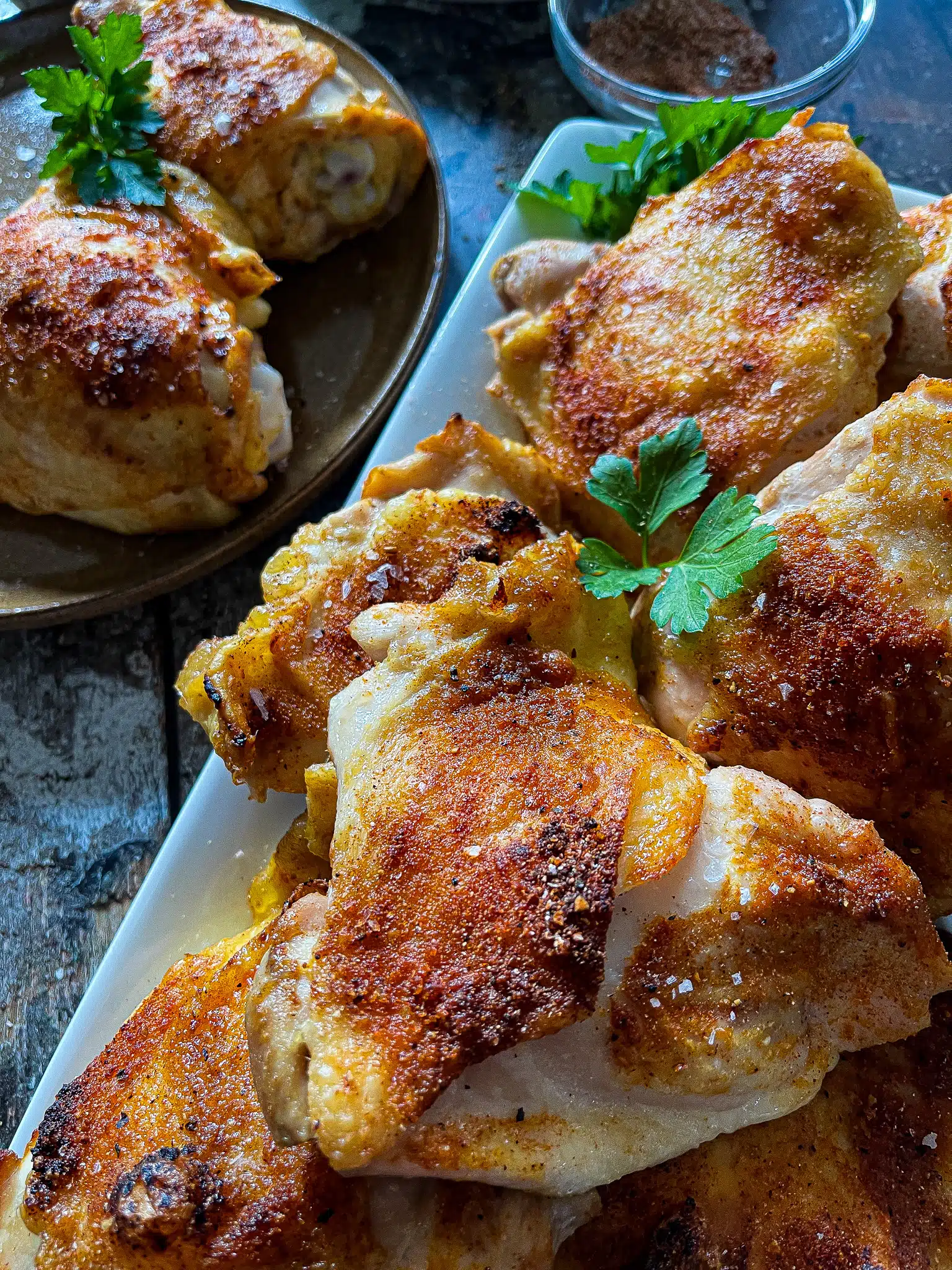 this is a close-up picture of roasted chicken thighs garnished with fresh parsley leaves