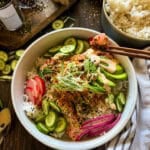 this is a picture of a sushi bowls with pickled onions and radish, salmon, avocado and a green onion garnish with a side of spicy sriracho mayo