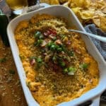 jalapeño popper dip in a white serving dish garnished with peppers and green onions