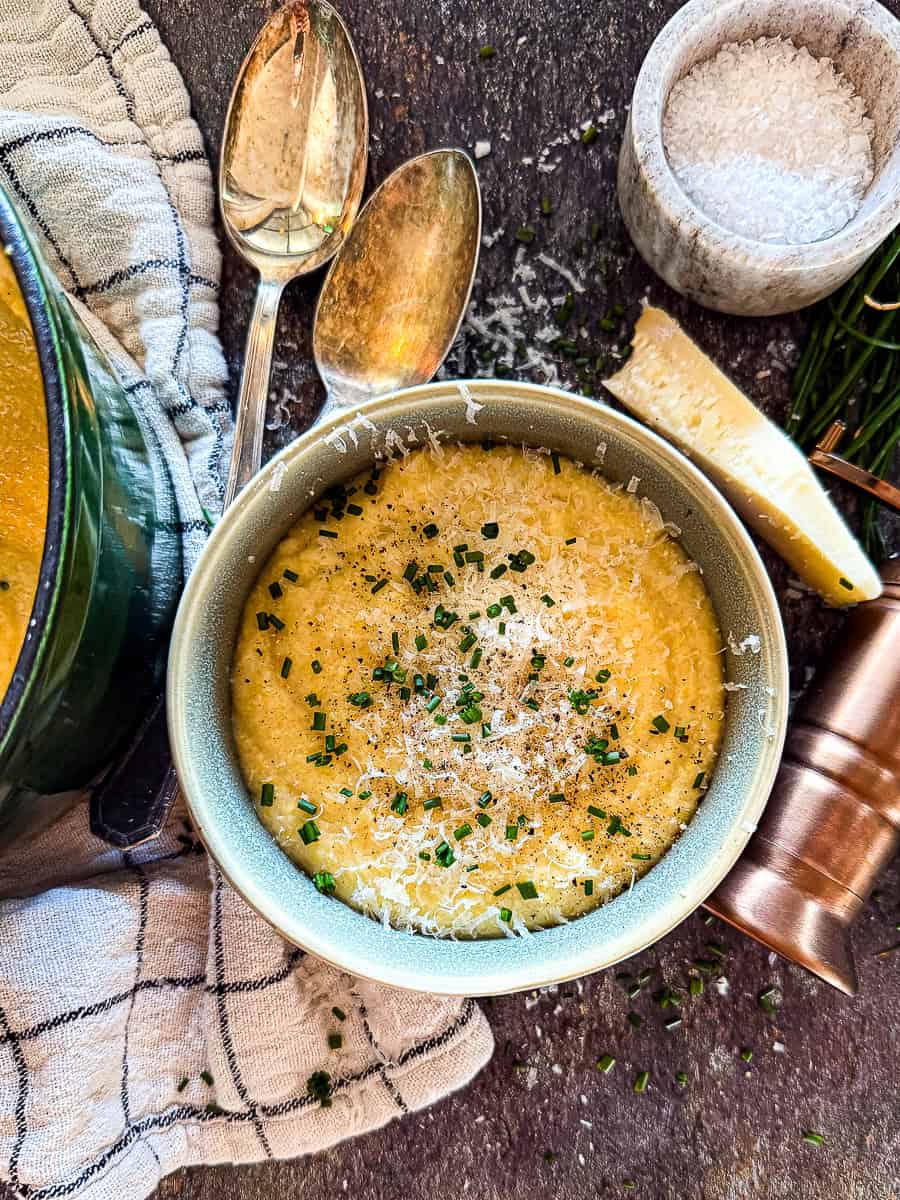 Bowl of creamy, golden polenta topped with butter and herbs — silky, rich, and perfect for cozy dinners