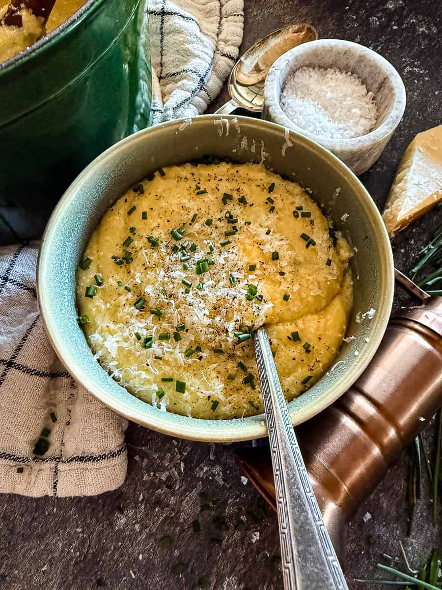 Bowl of creamy, golden polenta topped with butter and herbs — silky, rich, and perfect for cozy dinners