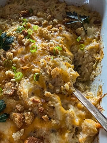 Baking dish with crab & artichoke dip with toasted breadcrumbs and fresh herb garnish