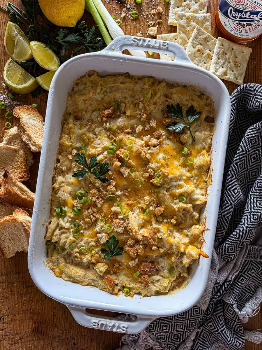 Baking dish with crab and artichoke dip with toasted breadcrumbs and fresh herb garnish
