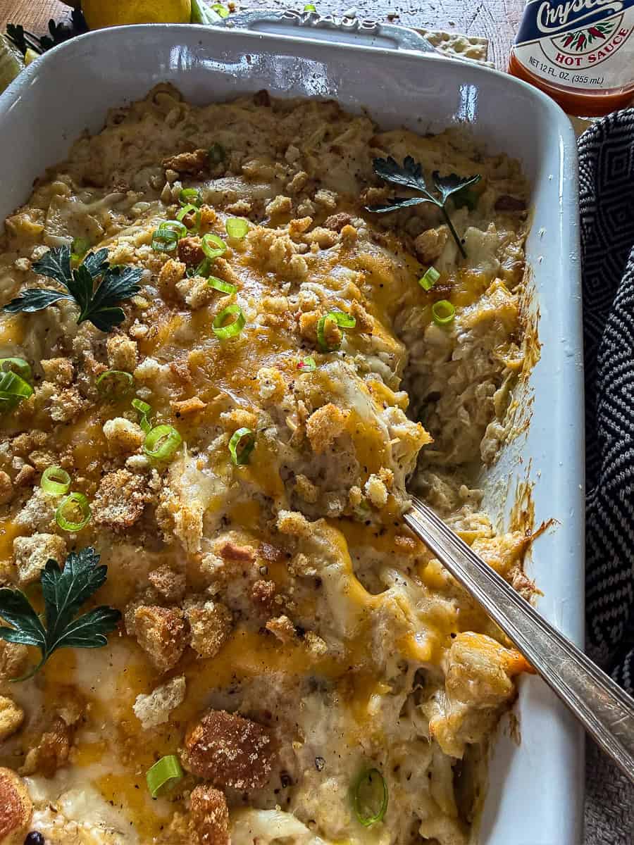 Baking dish with crab and artichoke dip with toasted breadcrumbs and fresh herb garnish
