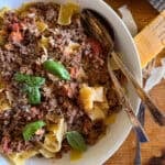bowl of creamy bolognese tossed with pappardelle pasta and garnished with basil leaves