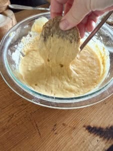 picture of sausage patty being dipped into a pancake batter