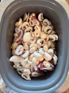 slow cooker bowl with pork chops, mushrooms, and onions