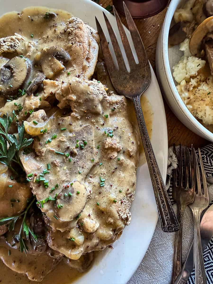 slow cooker smothered pork chops garnished with fresh herbs