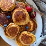 pancake sausages on a white serving platter garnished with berries