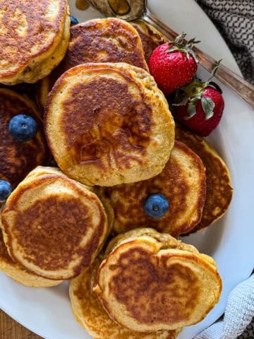 pancake sausages on a white serving platter garnished with berries