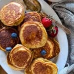 sausage pancakes on a white serving platter garnished with fresh berries