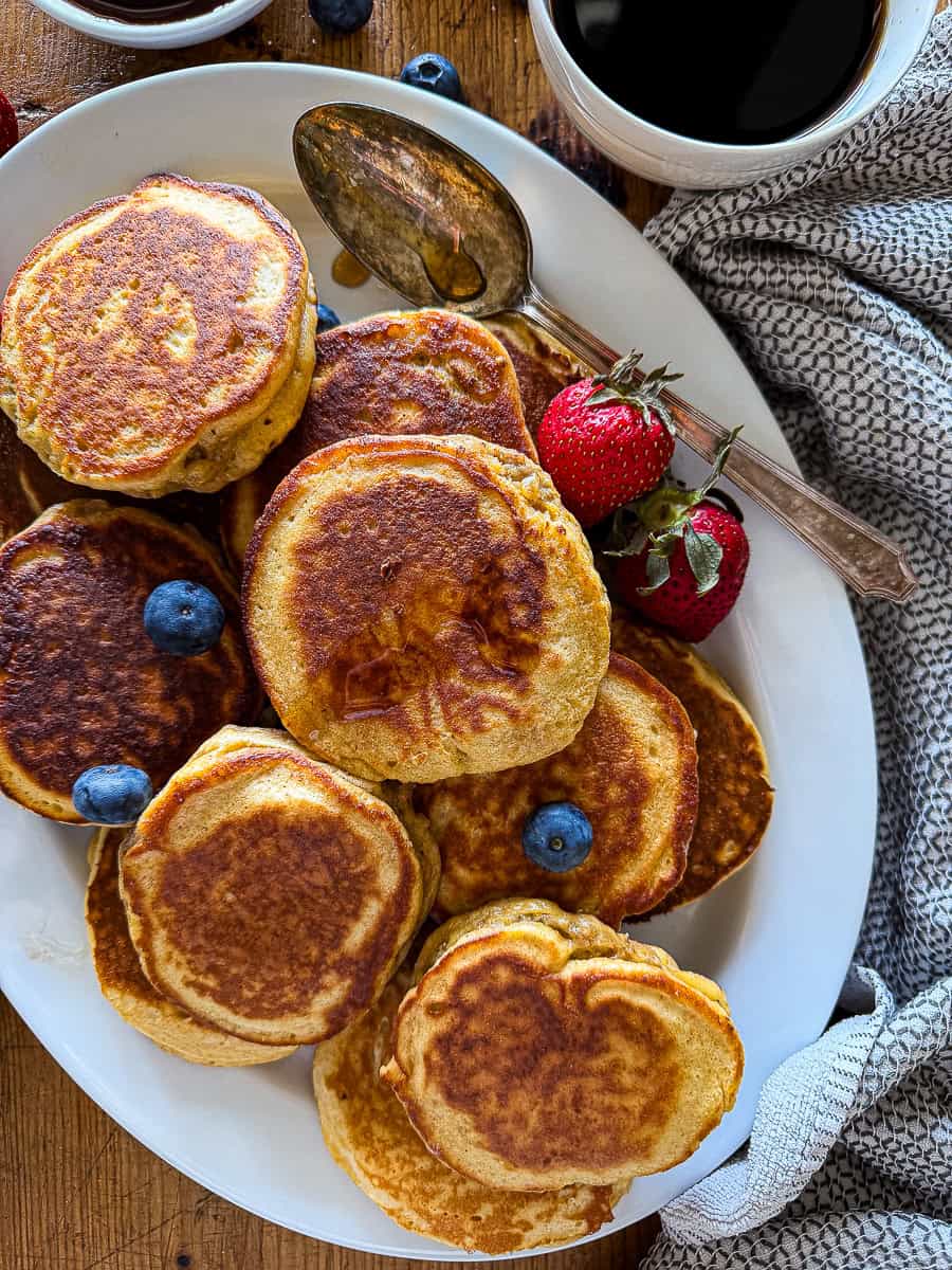 sausage pancakes on a white serving platter garnished with fresh berries