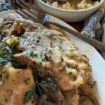 slow cooker smothered pork chops garnished with fresh herbs