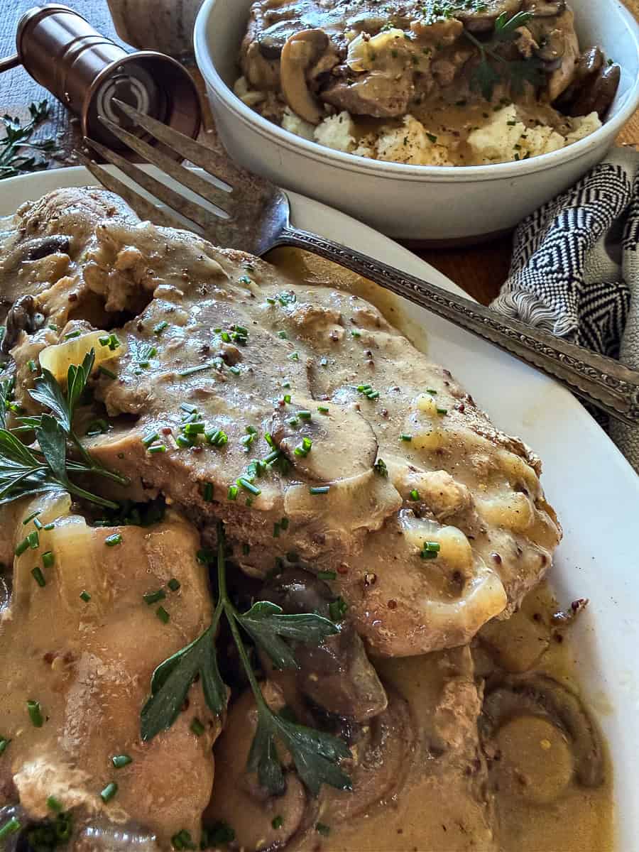 slow cooker smothered pork chops garnished with fresh herbs