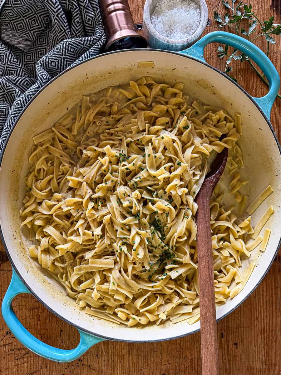 cafeteria noodles in large braiser with a wooden spoon