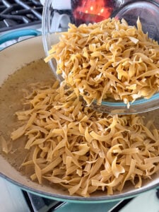 adding egg noodles to a large pot