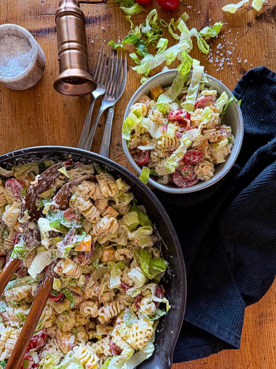 Fresh bacon ranch pasta salad with vegetables and creamy dressing on a wooden table.